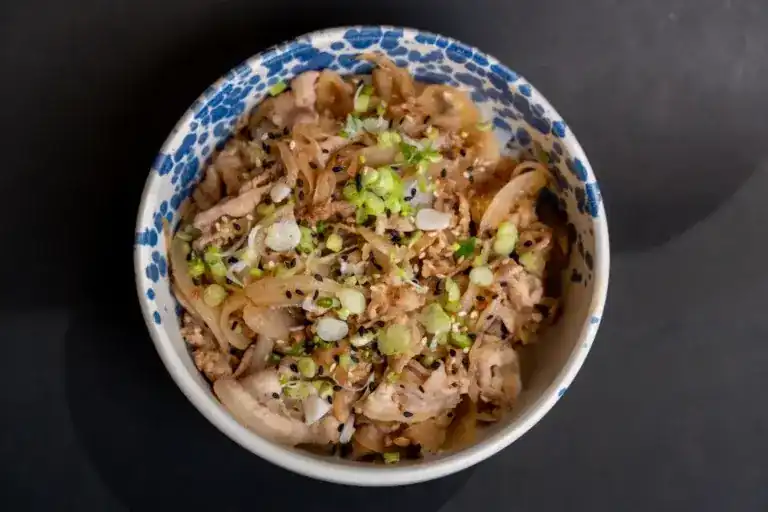 Pork sukiyaki rice bowl with onion and sesame