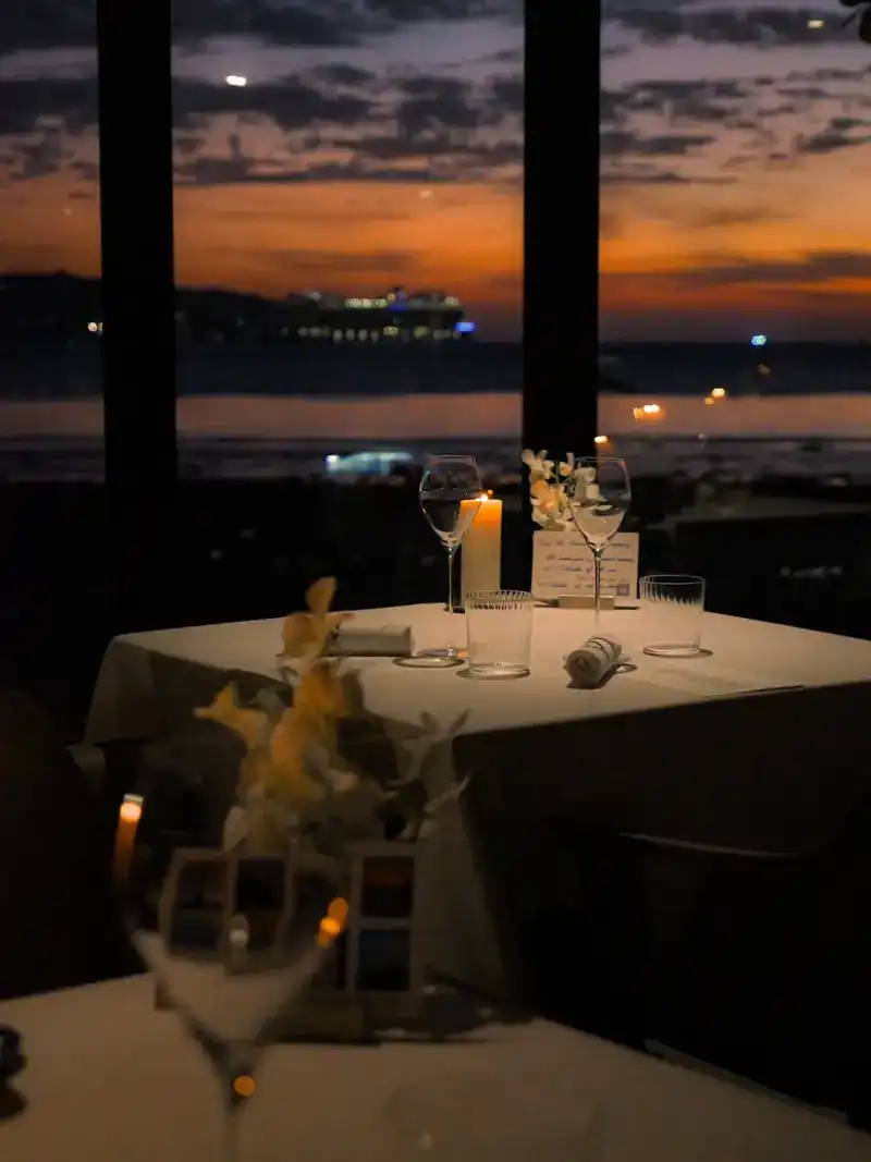A candlelit table for two by the window after sunset, lights out on the bay