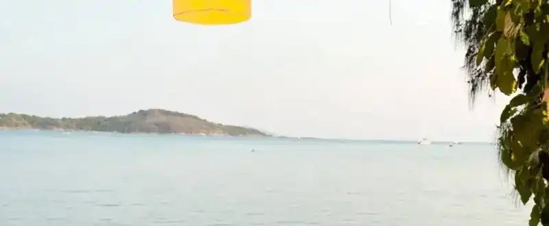 Calm sea and a green island seen from the beachfront