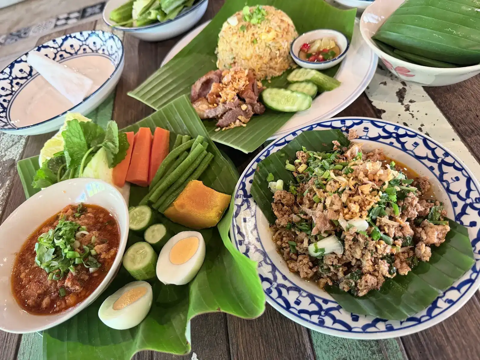 A chilli dip with fresh vegetables and boiled egg, larb on a banana leaf, and fried rice with pork