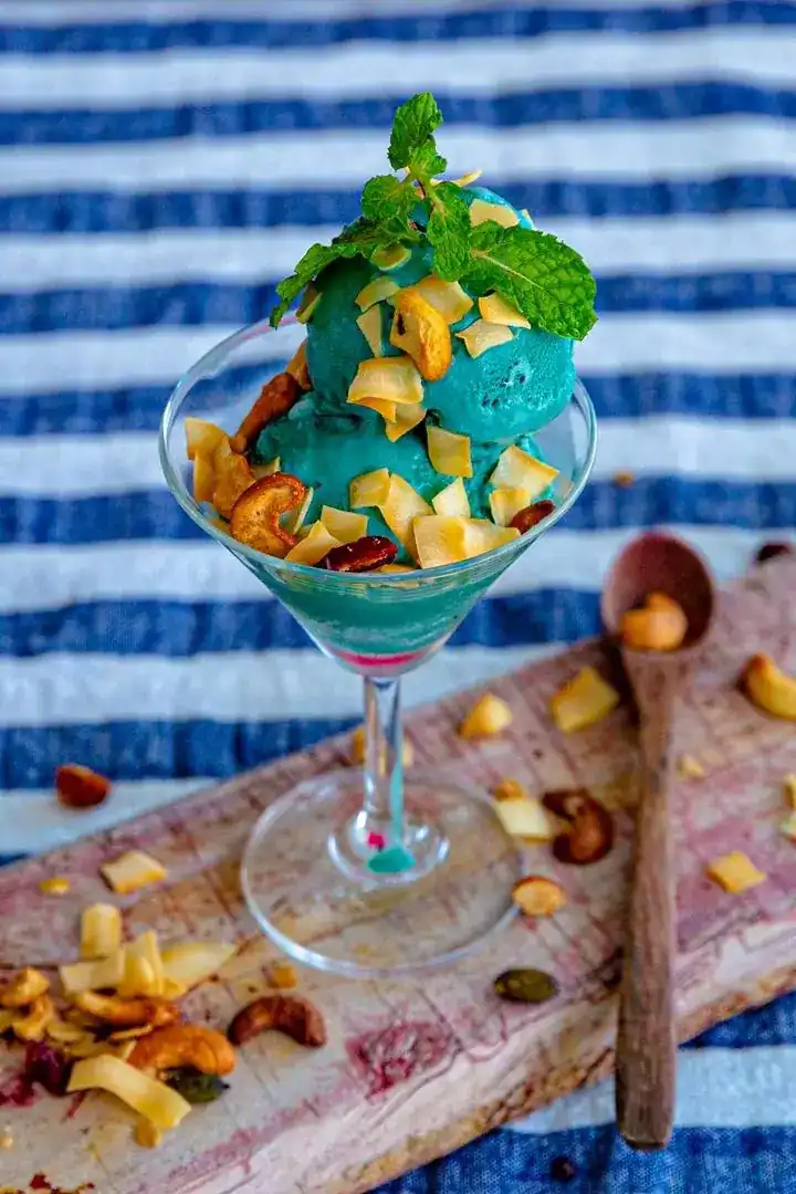 Blue ice cream in a glass topped with dried fruit