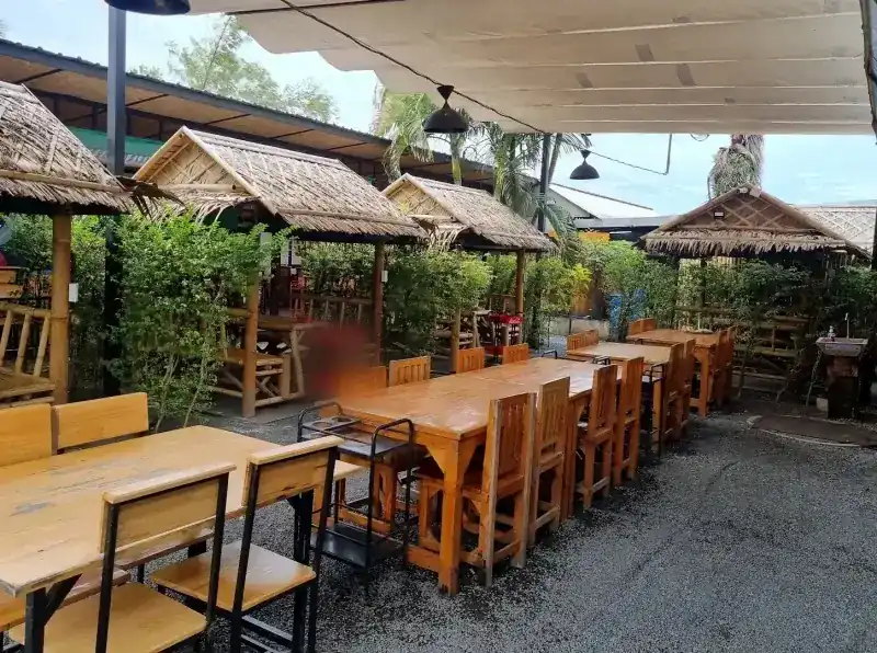 The garden: long wooden tables, thatched huts and canvas shades