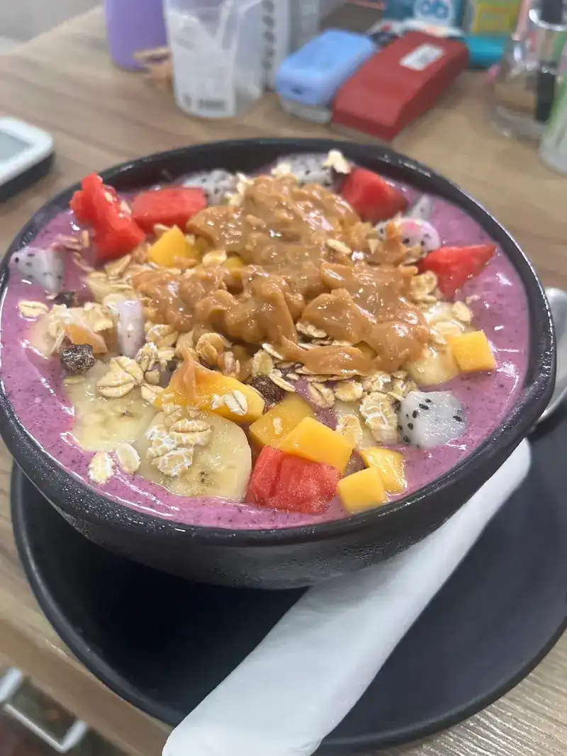 A purple smoothie bowl topped with fresh fruit and oats
