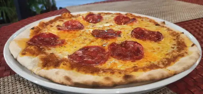 Salami pizza on a red woven placemat