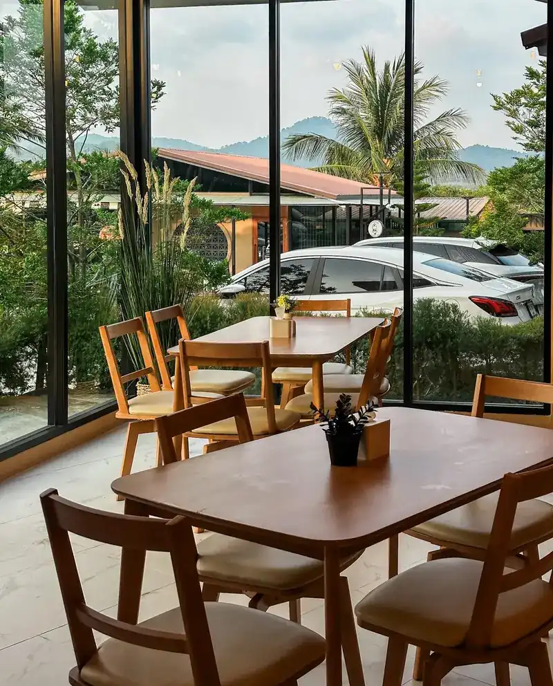 The dining room: wooden tables by tall windows, with hills beyond