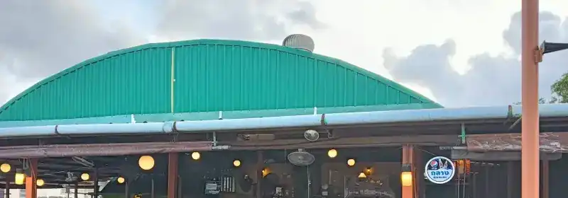 The restaurant's green arched roof over an open dining hall hung with round lamps