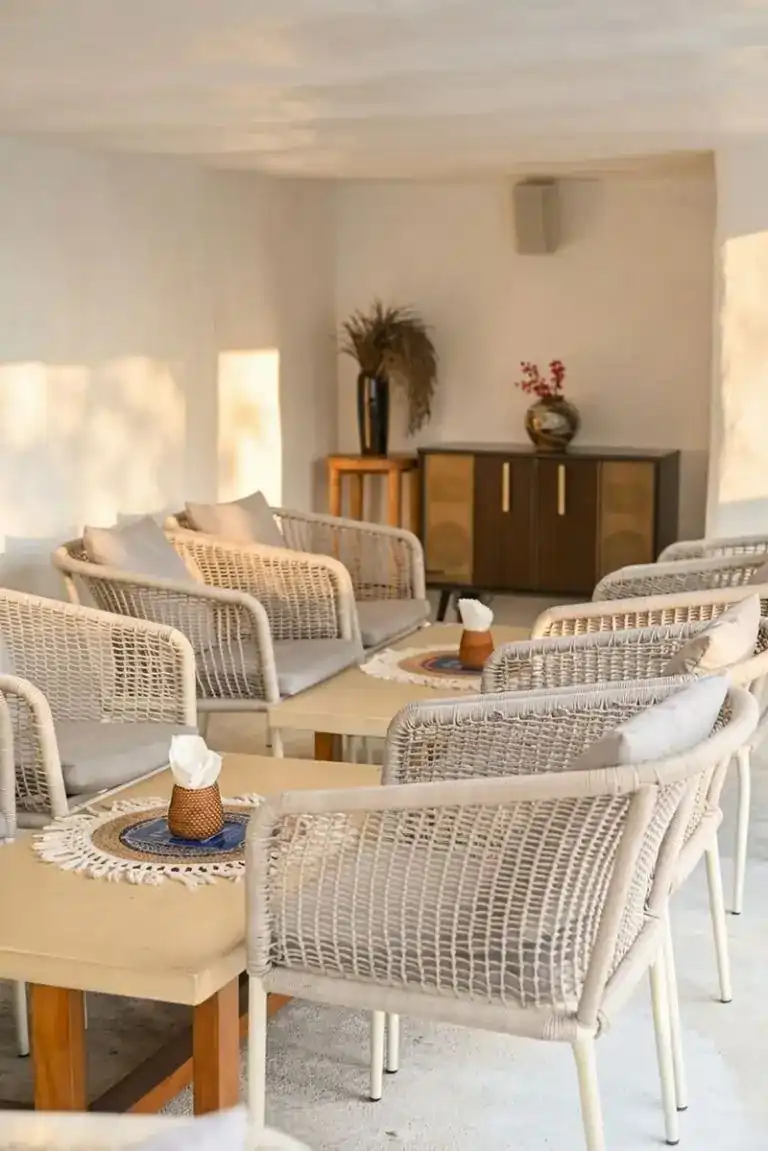 Woven rope armchairs around low tables in the whitewashed lounge, lit by afternoon sun