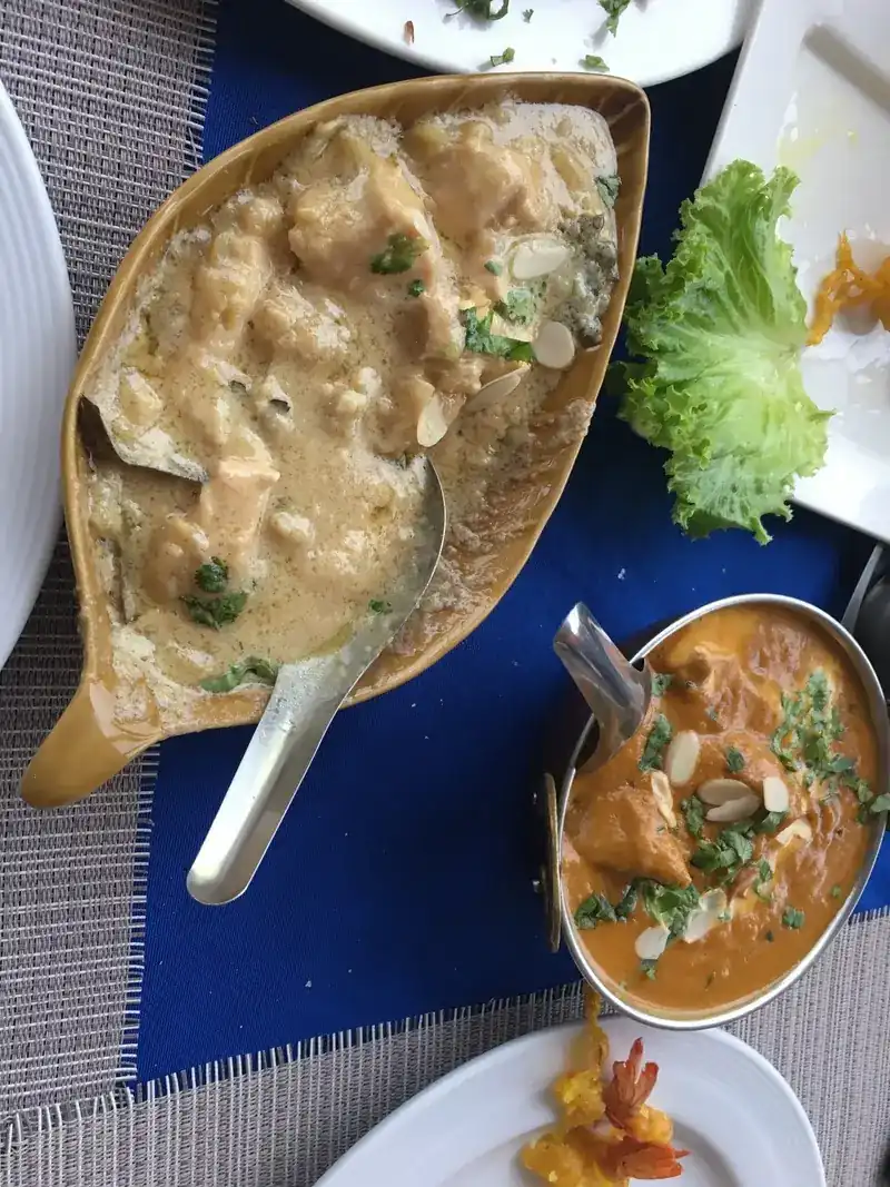 Two creamy curries with flaked almonds on a blue tablecloth
