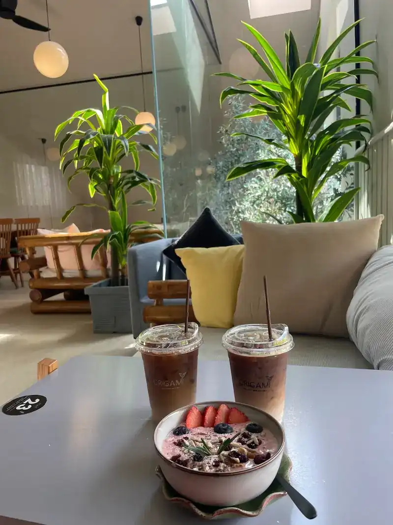 A pink bowl with granola and strawberries, and two iced drinks