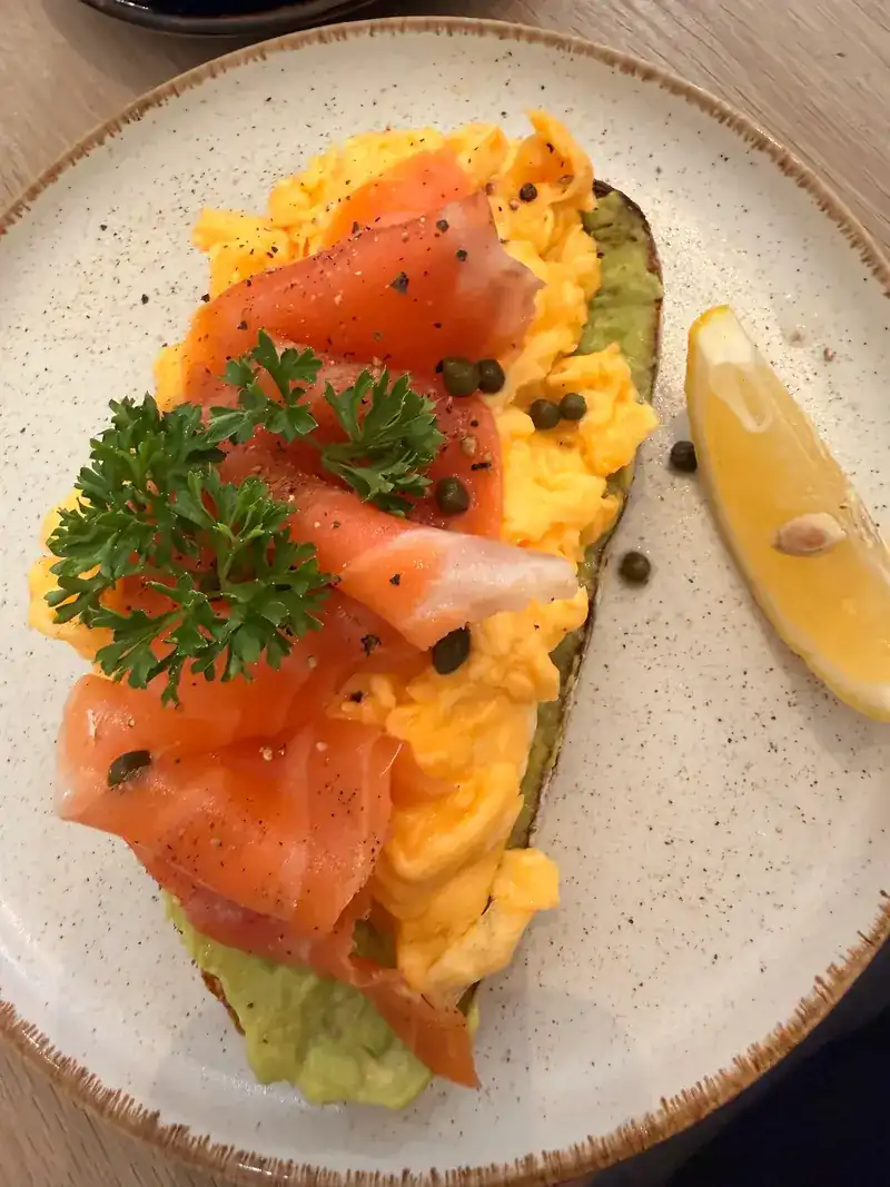 Scrambled eggs and smoked salmon on avocado toast, with capers and lemon