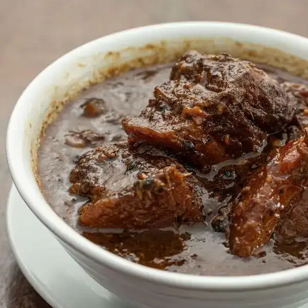 หมูฮ้อง: dark braised pork belly in a white bowl