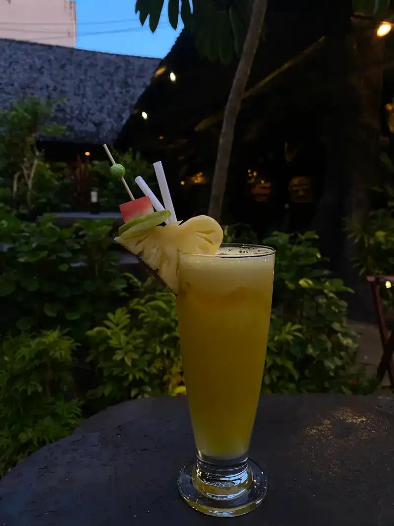 A tall yellow fruit drink with pineapple on the rim / เครื่องดื่มผลไม้สีเหลืองแก้วทรงสูง แต่งขอบแก้วด้วยสับปะรด