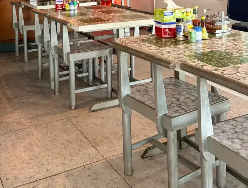 Dining tables and silver stools topped with a river-stone print, on a speckled tile floor