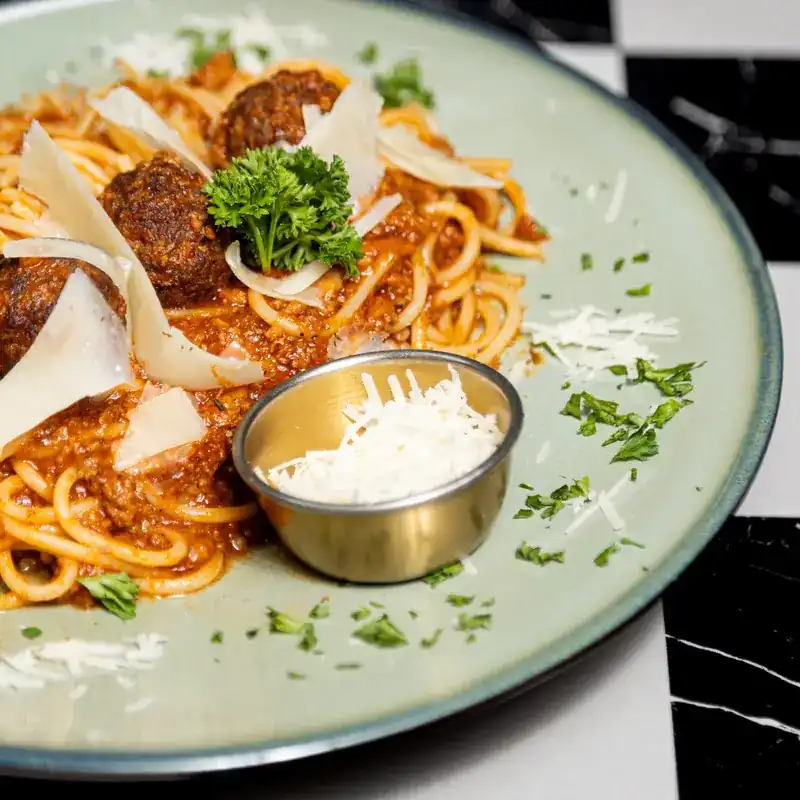 Spaghetti with meatballs, shaved cheese and parsley