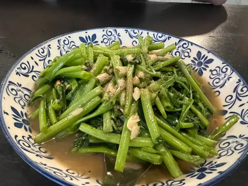 Stir-fried morning glory with garlic on a blue-and-white plate / ผัดผักบุ้งกับกระเทียมบนจานลายคราม