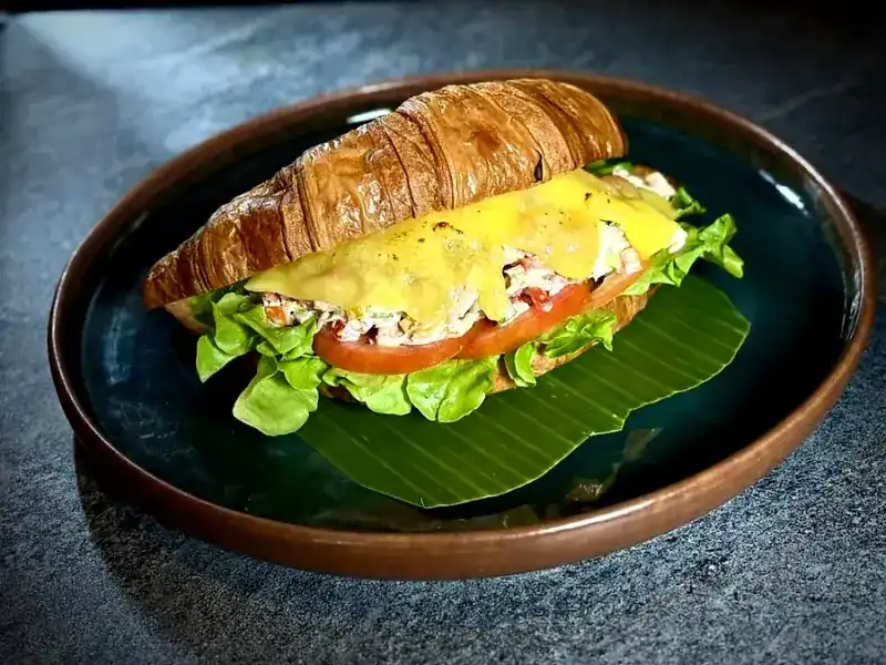 Tuna Melt Croissant with lettuce and tomato on a banana leaf