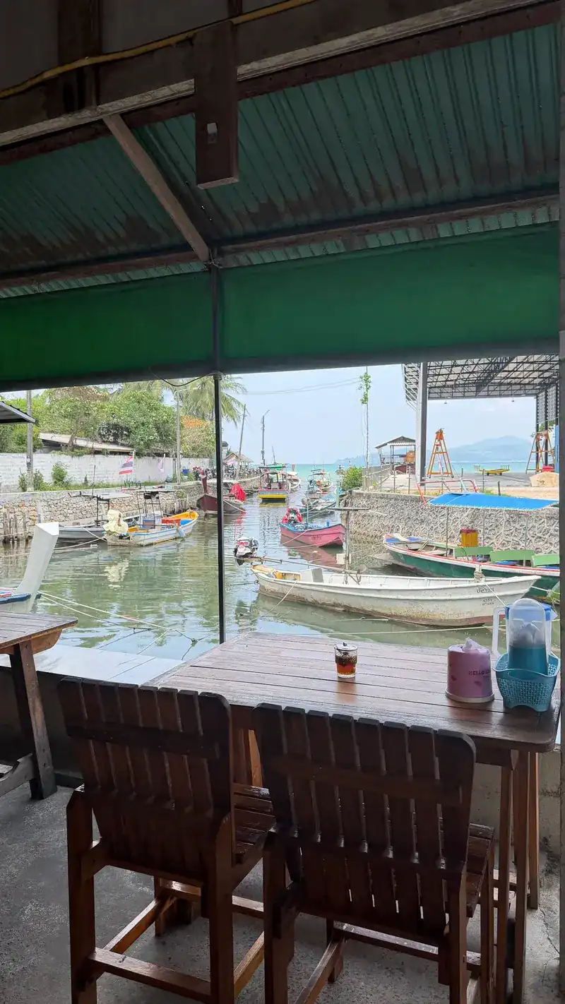 A wooden table under the green awning, looking out over the canal and its boats