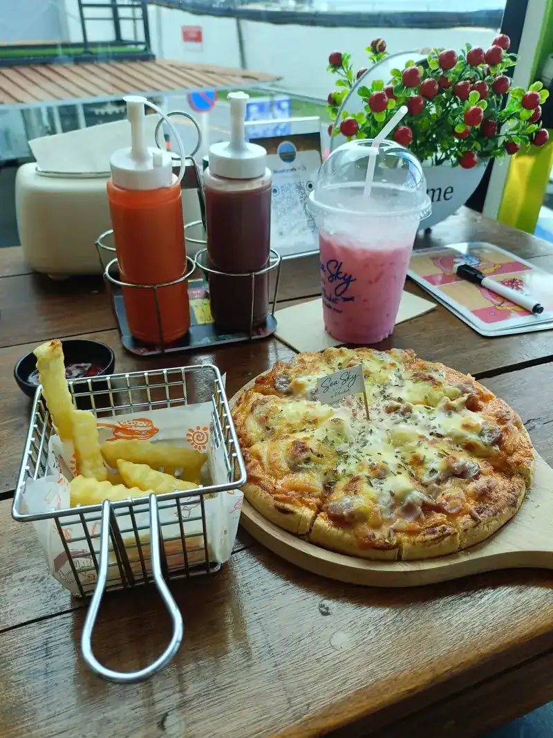 Pizza and fries on a wooden board, with a pink iced drink