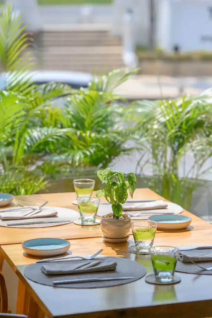 A wooden table laid for lunch with palm fronds behind it