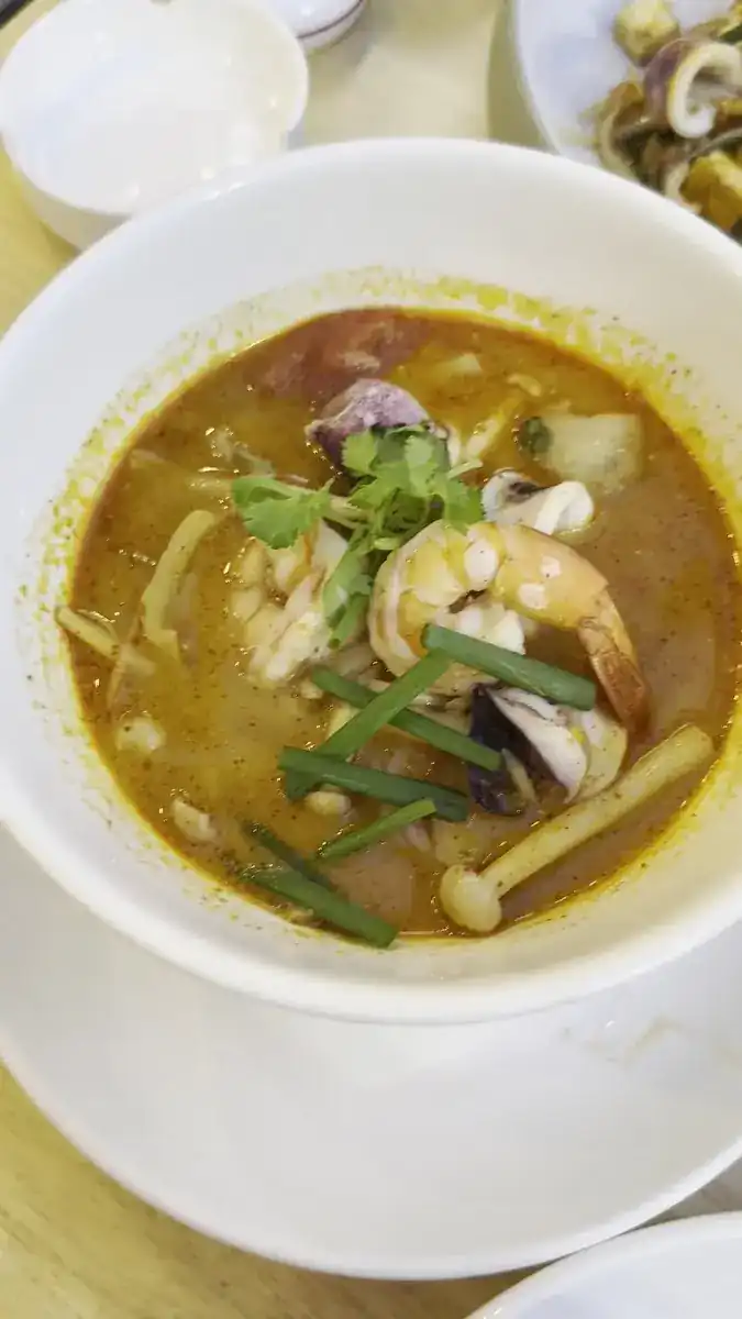 A bowl of soup with prawns, squid and mushrooms