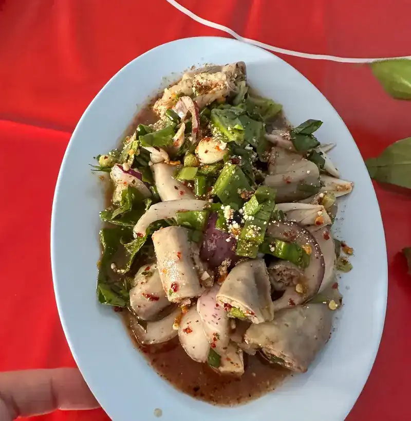 Spicy salad with herbs and red onion, held over a red table
