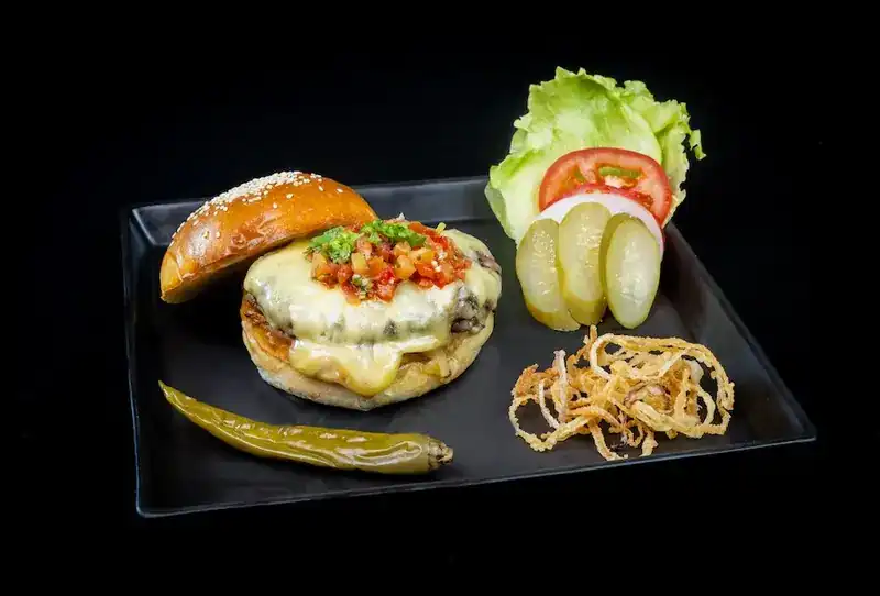 Open cheeseburger with tomato salsa, pickles, lettuce and crispy onions