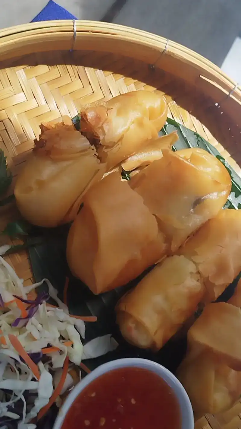 Crisp spring rolls in a bamboo basket with sweet chilli sauce