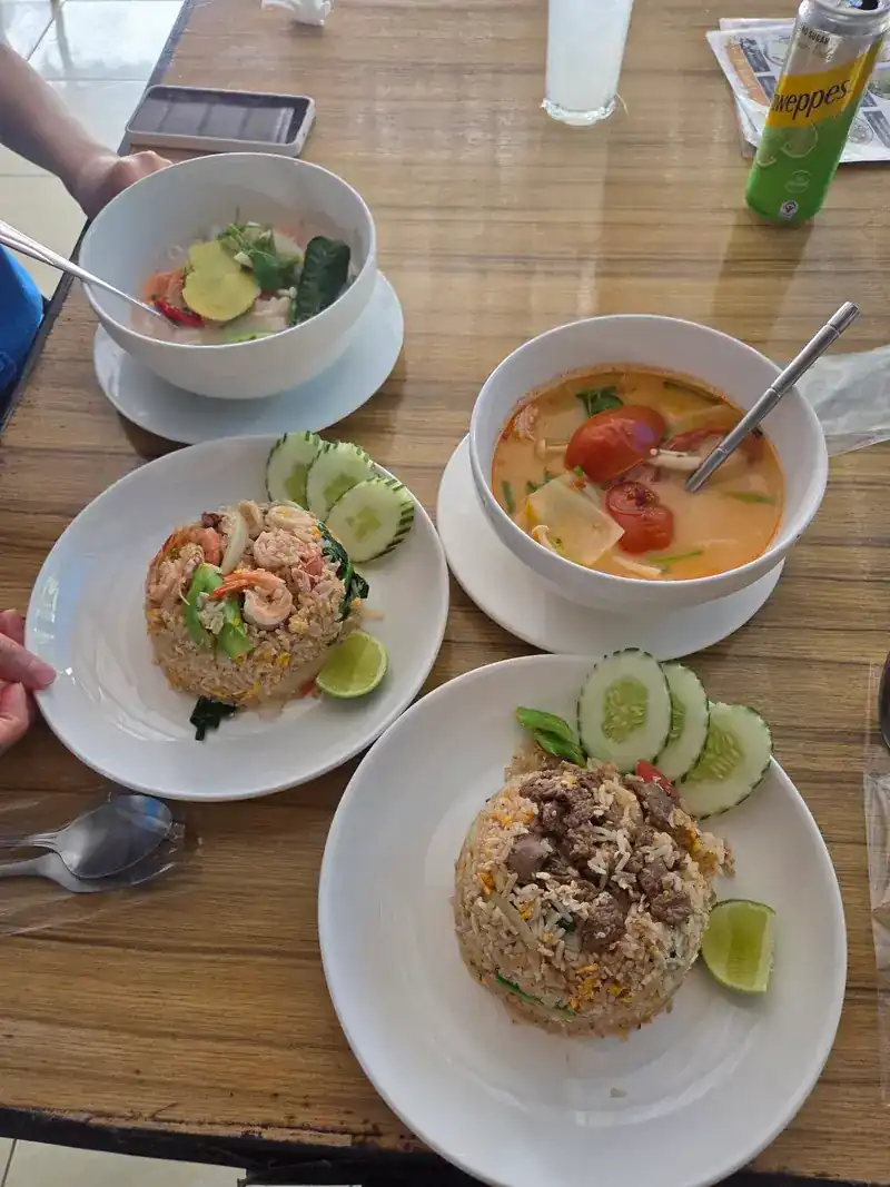 Two plates of fried rice and two bowls of soup on a wooden table