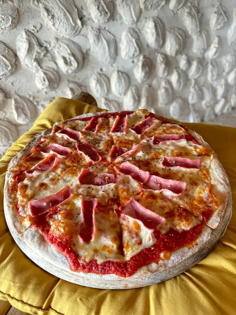 A thin-crust pizza with ham and melted cheese.