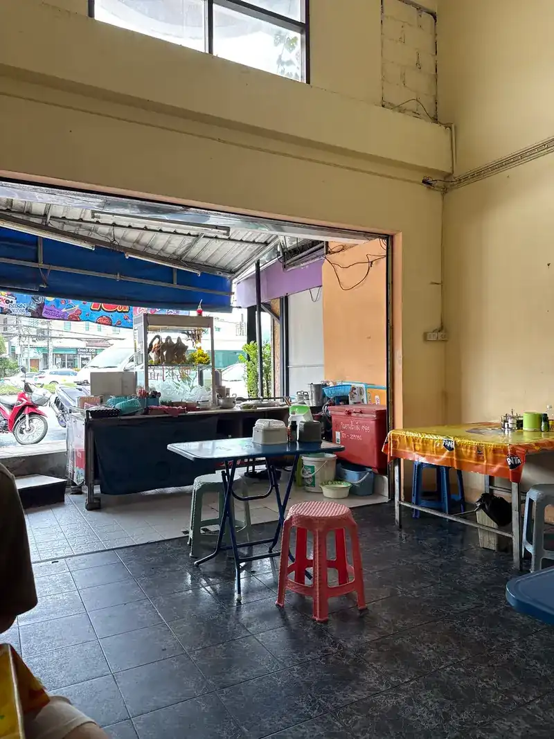 Inside the shop: tiled floor, a red plastic stool and the front open to the street