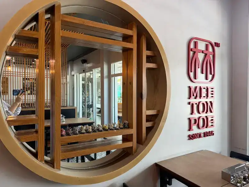 Inside: a round wooden window with shelves of small figurines, beside the red Mee Ton Poe sign