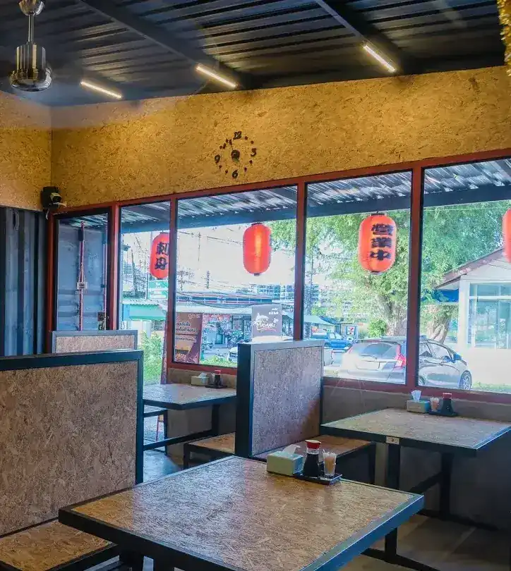 Inside: chipboard booths and tables by red-framed windows hung with red paper lanterns