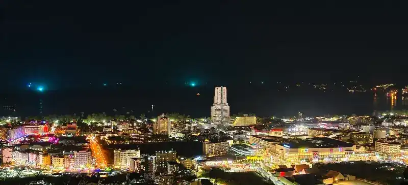 Patong at night, the whole town lit up between the hill and the dark sea