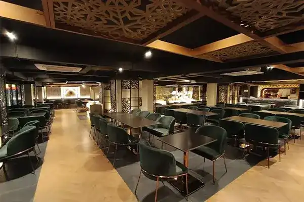 Dining room with dark green chairs, wooden tables and carved lattice ceiling panels