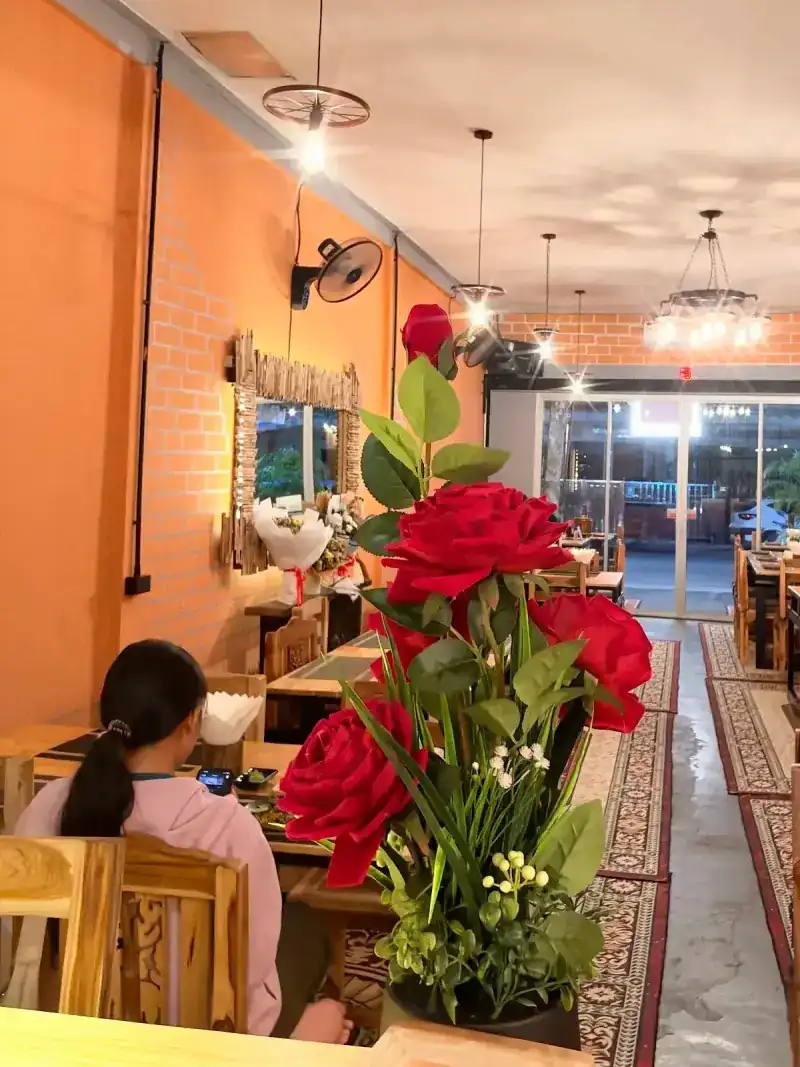 Inside: orange brick walls, wheel lights, patterned rugs and a vase of red roses