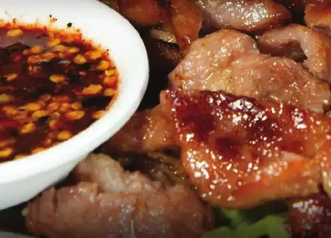 Grilled pork with a bowl of chilli dipping sauce