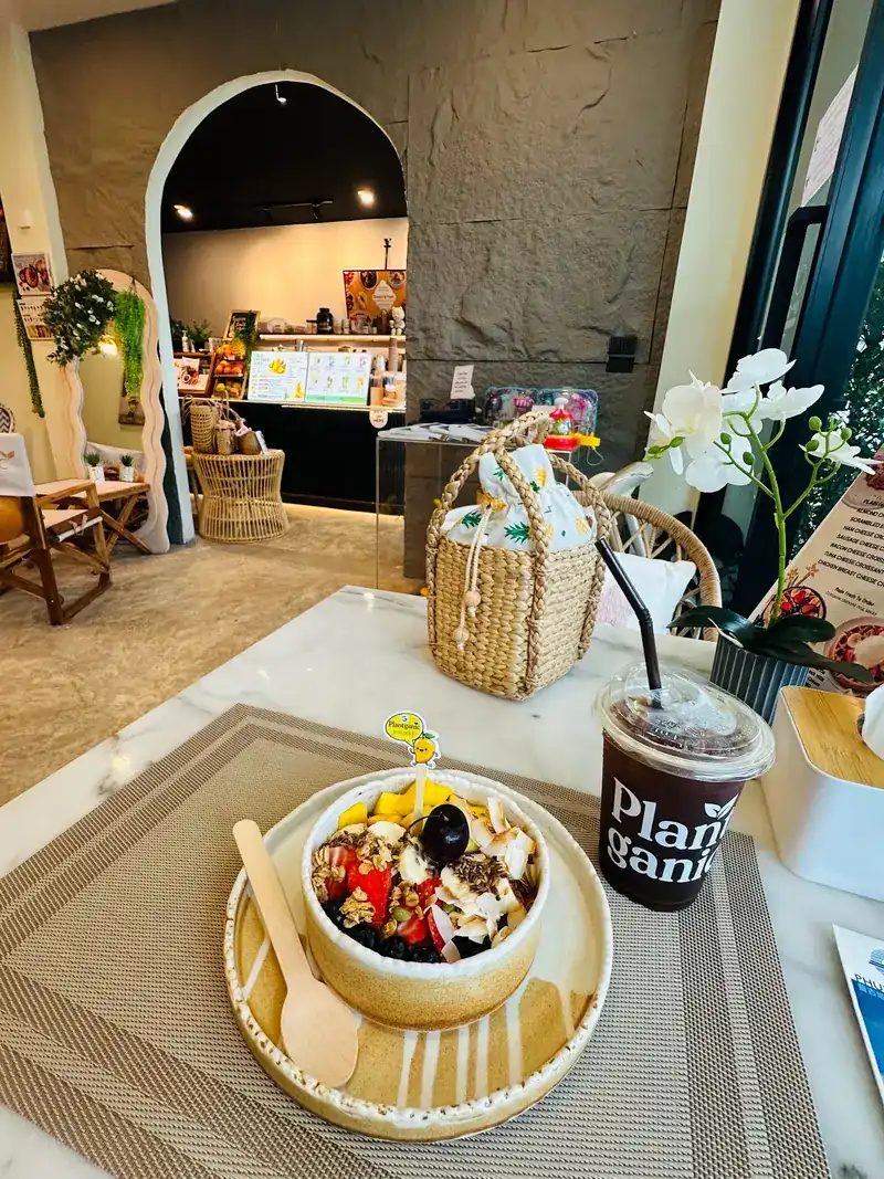 Acai bowl and an iced drink on a table, the arched doorway and counter behind