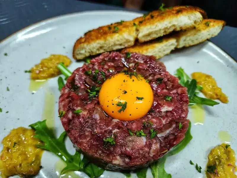 Beef tartare with a raw egg yolk, rocket and toasted bread