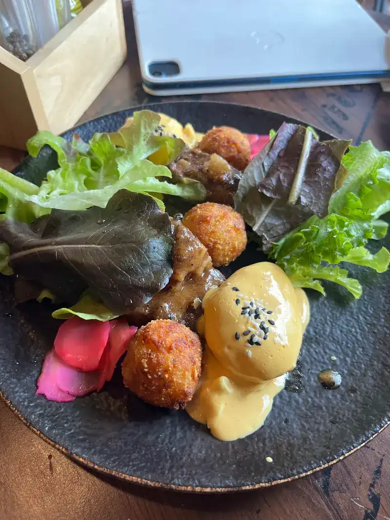 An egg with hollandaise, croquettes and greens