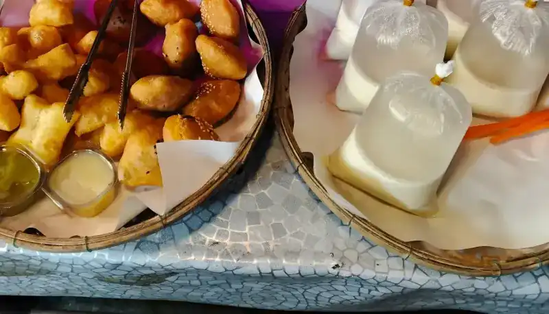 Bags of soy milk beside a basket of patongko and buns