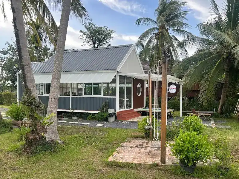 The Mama Kitchen house in a garden of coconut palms, with a swing in front