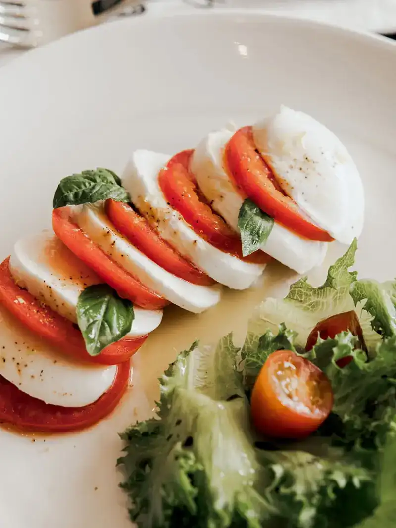 Slices of tomato and mozzarella with basil leaves