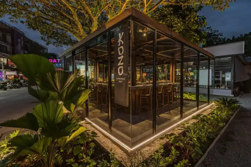 KOZO's glass pavilion under the trees on Boat Avenue in the evening