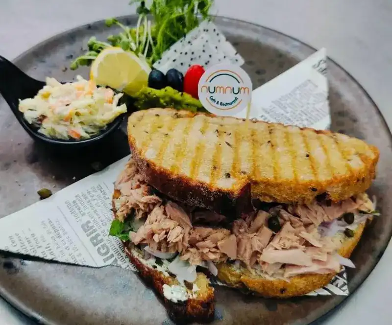 Grilled sandwich with coleslaw and a lemon wedge