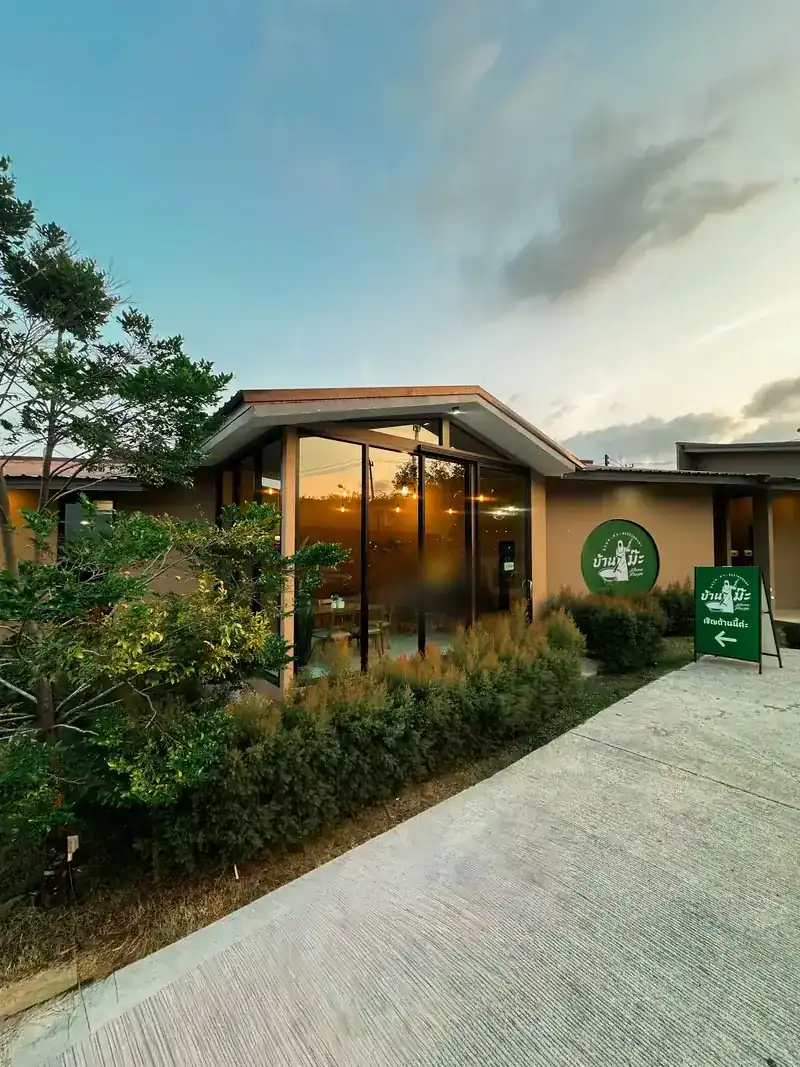 Baan Ma at dusk: the glass front, the green sign and the garden path