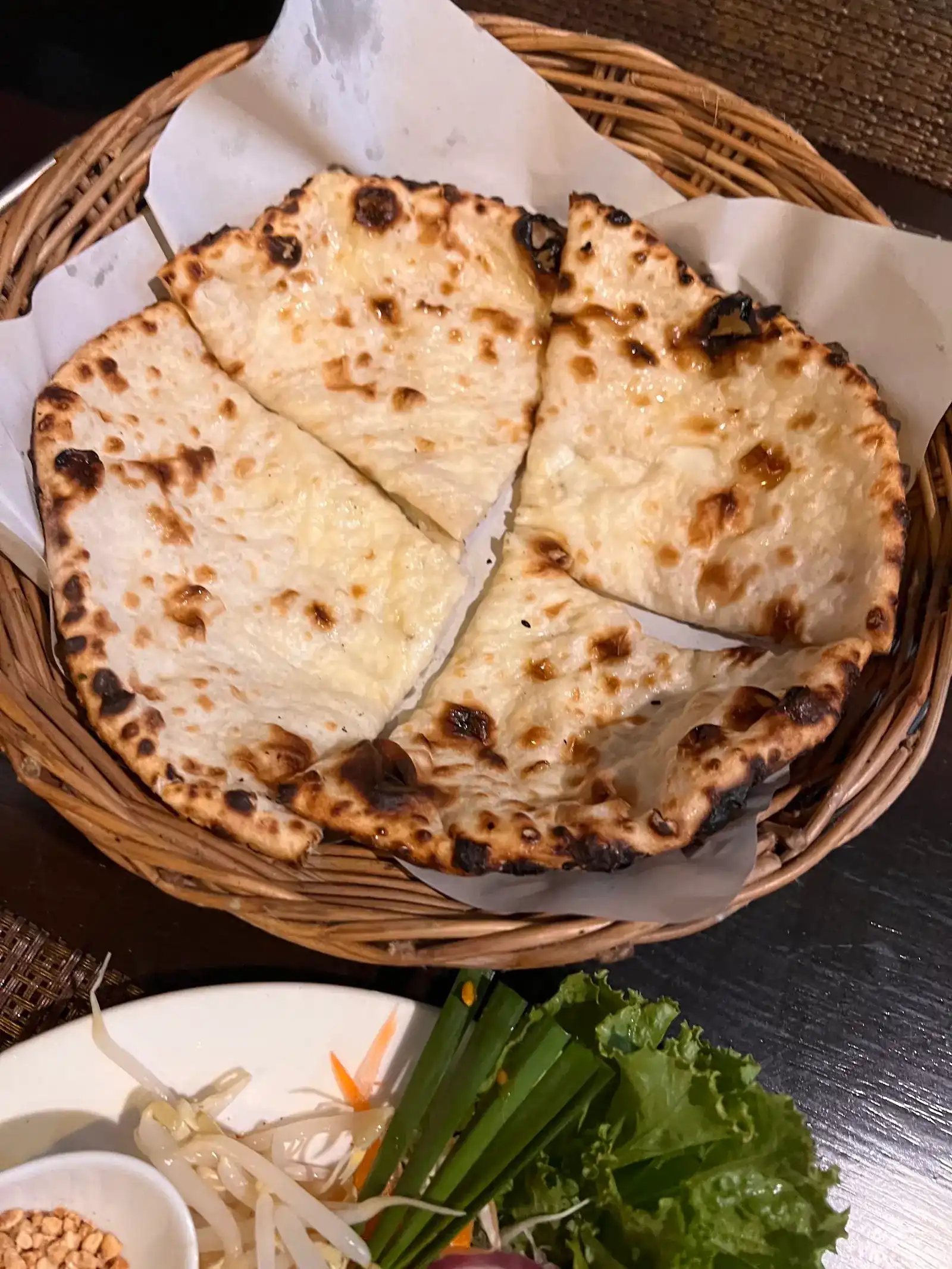 Nan bread from the oven, cut in four, in a wicker basket