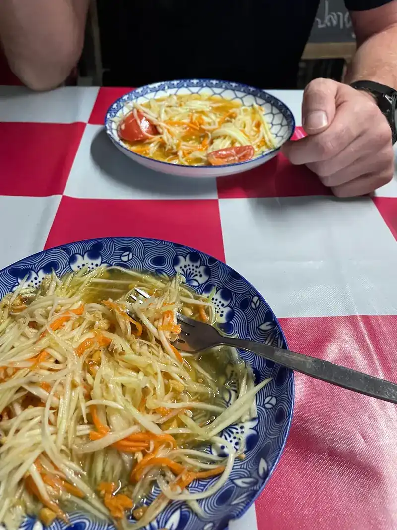 Green papaya salad in blue-and-white bowls on the checked cloth