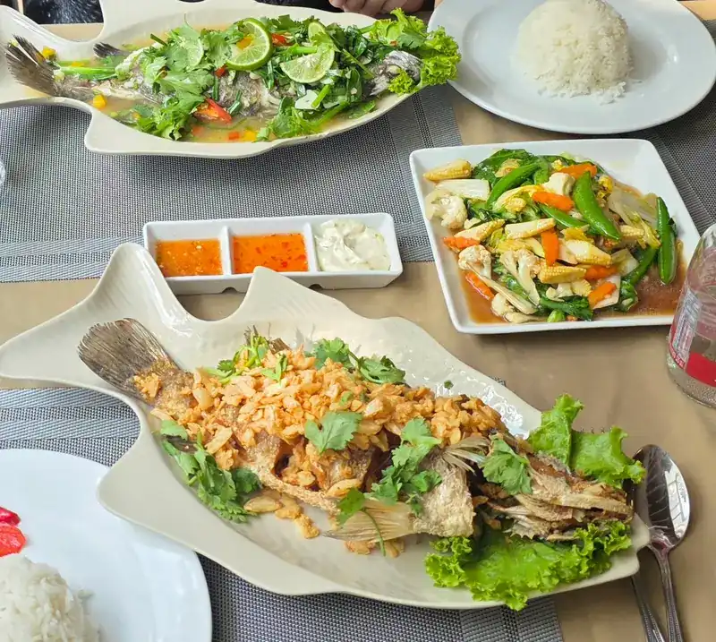 A whole fried fish under crisp garlic, a steamed fish with lime, stir-fried vegetables and rice
