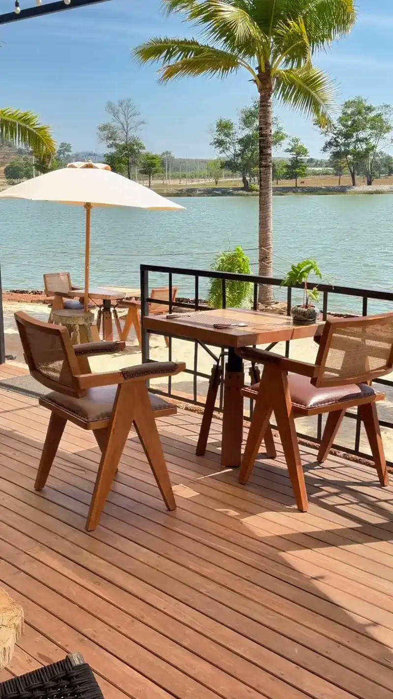 Wooden chairs and a parasol on the deck by the water