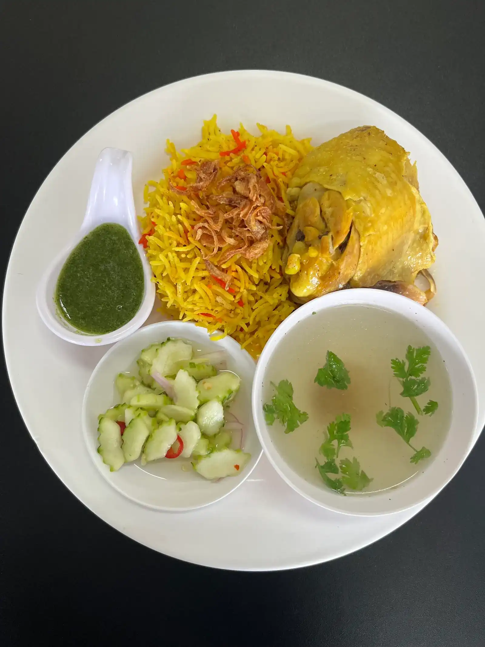 Chicken biryani: yellow rice with fried shallots and chicken, green dipping sauce, cucumber relish and clear soup